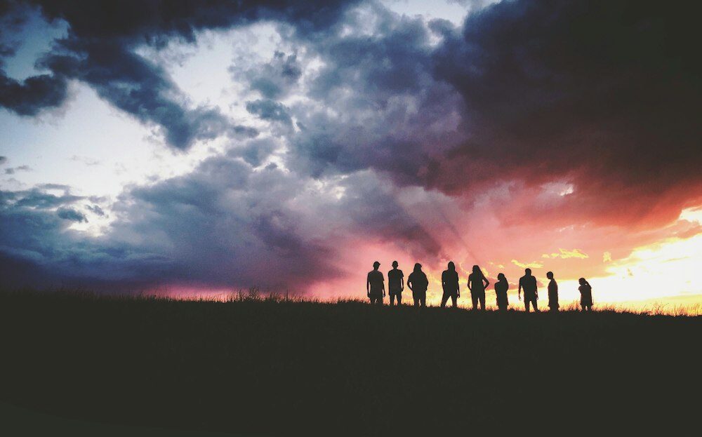 silhouette of nine persons standing on the hill